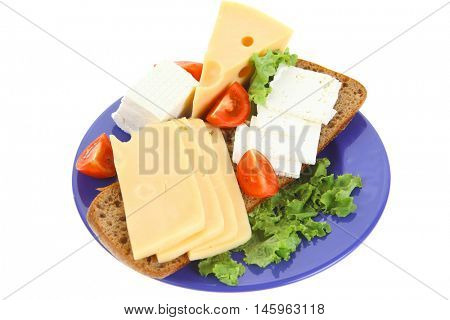 set of gourment cheese slice and chunk ( bar)  white goat greek yellow french aged on half of rye bread on green lettuce salad with tomatoes on blue plate isolated over white background