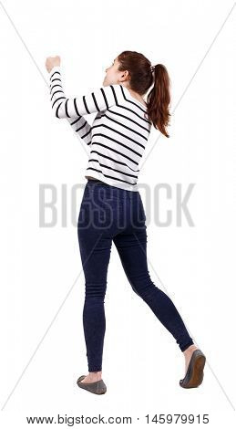 back view of standing girl pulling a rope from the top or cling to something. girl watching. girl in a striped sweater, pulling a rope from the top.
