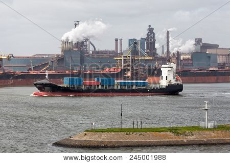 Big Steel Factory In Harbor Ijmuiden With Cargo Carriers And Container Ship In Front, The Netherland