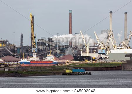Big Steel Factory In Harbor Ijmuiden With Cargo Carrier In Front, The Netherlands