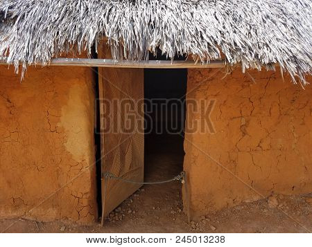 Open Door Of Brown And Red Adobe Or Clay Building With Straw Roof