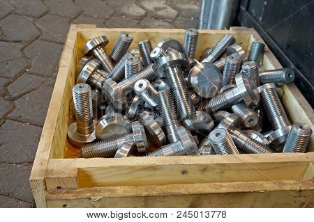 Processing Of Metal By Cutting At A Manufacturing Plant. New Bolts And Screws After Turning Are In A