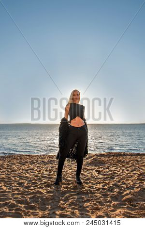 Portrait Of A Seductive Blonde Girl In Black Clothes With A Sunset Lake On A Background
