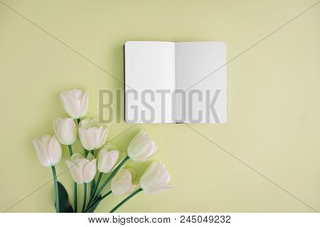 Opened Noteboog Around Beautiful Flowers. Yellow Background. Flat Lay Style.