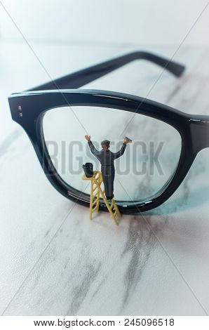 Optician Eyeglasses Being Cleaned By Tiny Figurine Symbolizing Clear Vision