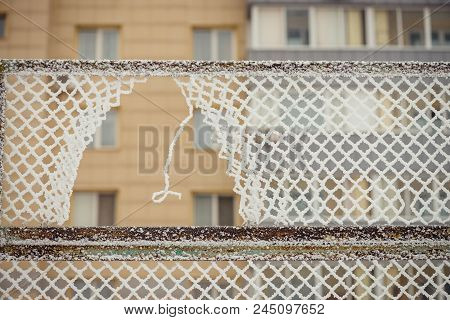 A Hole In The Fence. Rabitsa In The Hoarfrost. A Multi-storey Building On A Background.