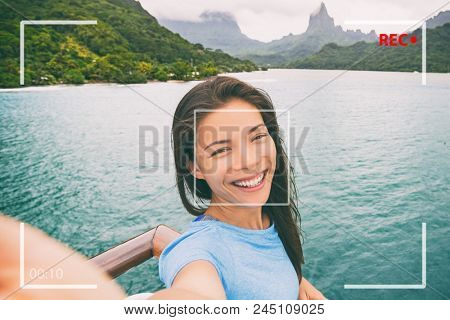 Travel tourist woman vlogging doing video vlog online during Tahiti luxury cruise vacation. Asian girl talking online doing video blog recording in Bora Bora island landscape.