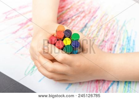 Drawing On A White Sheet Of Paper With Colored Wax Pencils. The Concept Of Children's Creativity And