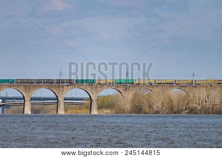 A Freight Train Is Driving Across A Bridge Across The River