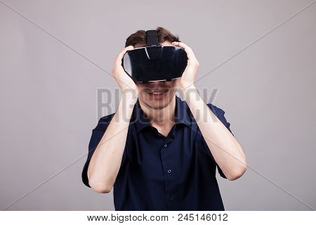 Excited Man Experiencing Virtual Reality For The Firts Time. He Is Wearing A Vr Headset. Gray Backgr