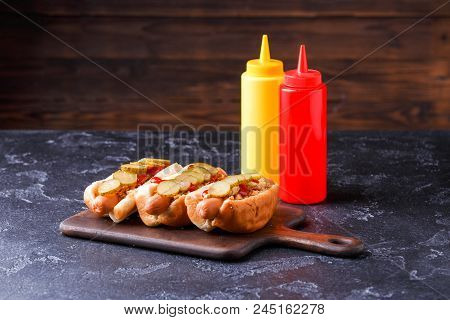 Image Of Hotdogs On Cutting Board At Table With Ketchup And Mustard