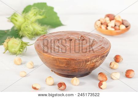 Sweet Chocolate Hazelnut Spread With Whole Nuts And Green Hazelnut On White Table. Nutella Cream.