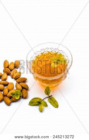 Beneficial And Essential Oil Of Badam Or Almonds With Its Beneficial Tea In A Transparent Cup Isolat