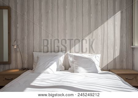 Bed Made-up With Clean White Pillows And Bed Sheets In Beauty Room. Close-up. Lens Flair In Sunlight