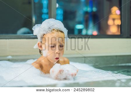 Happy Little Baby Boy Sitting In Bath Tub In The Evening Before Going To Sleep On The Background Of 