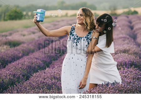 Sister having fun with bubble wand outdoor. Soap bubble fight. 