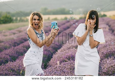Sister having fun with bubble wand outdoor. Soap bubble fight. 