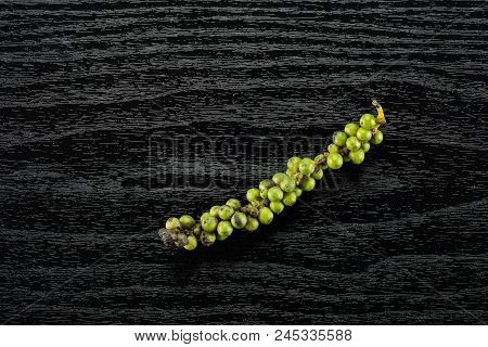 Unripe Drupes Of Fresh Black Pepper Flatlay On Black Wood Backgound One Bunch