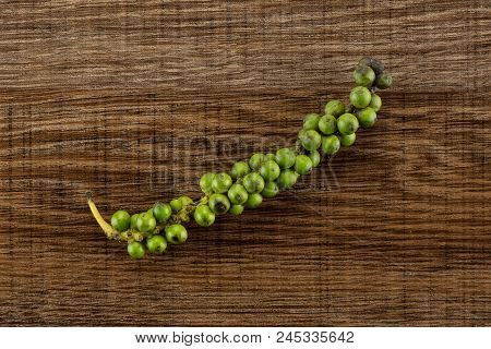 Unripe Drupes Of Fresh Black Pepper Flatlay On Brown Wood Backgound One Bunch