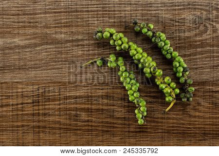 Unripe Drupes Of Fresh Black Pepper Flatlay On Brown Wood Backgound Three Bunches