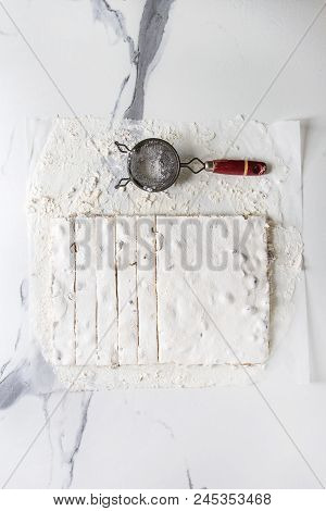 Homemade Honey Nuts Nougat Turron Sliced On Crumpled Paper With Vintage Sieve And Sugar Powder Over 