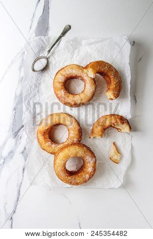 Homemade Puff Pastry Deep Fried Donuts Or Cronuts With Sugar On Crumpled Paper Over White Marble Tex