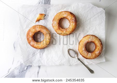 Homemade Puff Pastry Deep Fried Donuts Or Cronuts With Sugar On Crumpled Paper Over White Marble Tex