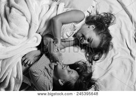 Childhood And Friendship Concept. Schoolgirls In Pink Pajamas Wallow On Colorful Pillows, Top View. 