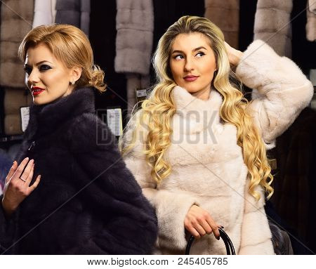 Women In Fur Coats With Bags In Fur Shop. Girls With Mysterious Faces In Black And White Fur Coats H
