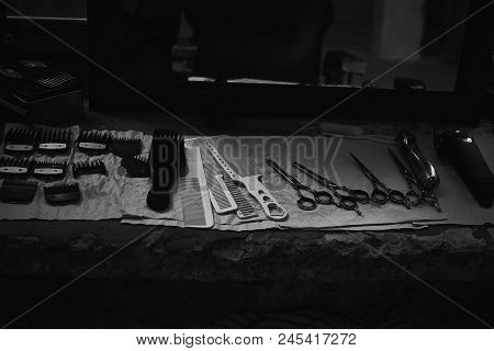 The Tools Of A Barber On The Desktop In Front Of The Mirror .black And White Photo Of Hairdresser To