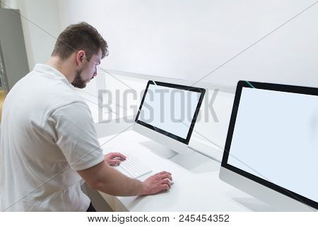 Man With A Beard Uses A Computer Monoblock With A White Screen In A Technology Store. Choosing A Com