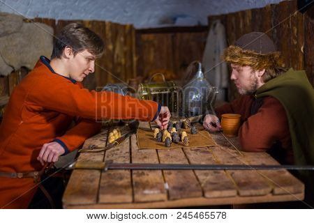 Two Men In Russian Ethnic Suit Playing Medieval Popular Strategy Board Game - Tafl. Folk, Competitio