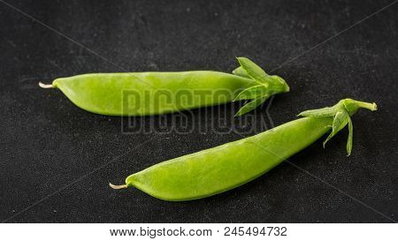 Freshly picked snow peas on a black background.