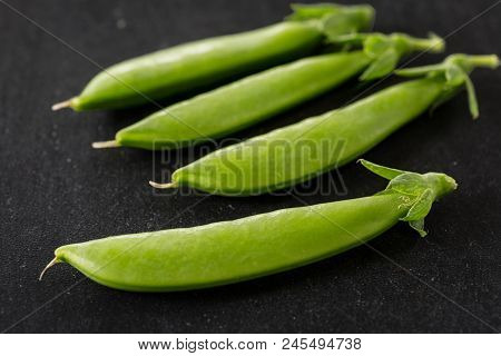 Freshly picked snow peas on a black background.