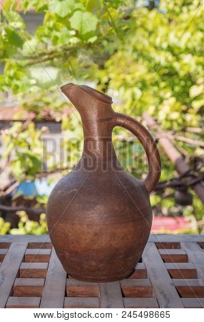 A Clay Wine Jug With Grape Leaves Background