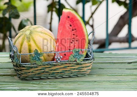 Seasonal Fresh Fruits, Watermelon And Rockmelon In Basket On Garden Table