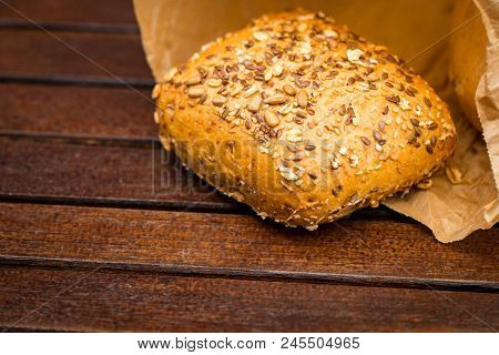 Fresh Baked Bread Wrapped In Paper, On Wooden Background