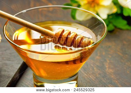 Honey With Wooden Honey Dipper On Wooden Table