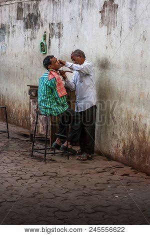 A Street Barber Shaves A Customer On Streets Of Mumbai
