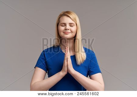 Young Blonde Woman Practising Yoga, Holding Hands In Namaste And Keeping Her Eyes Closed. Caucasian 