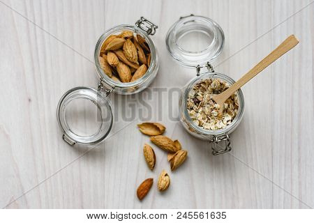 Still Life Of Healthy Food And Diet Food, Almonds, Wooden Spoon And Muesli In Glass Jars On A Wooden