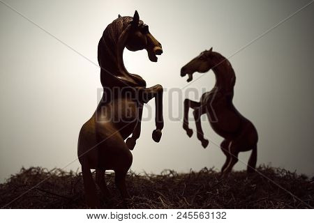 Silhouette A Pair Of Skittish Horse Or Fighting In Grass Filed, The Wood Horse Sculpture Is In Drama