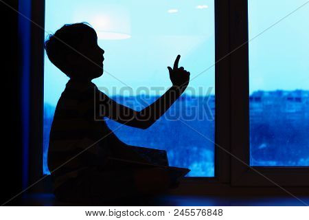 Parents And Kids Sitting Near Window And Having Fun At Home. Silhouette View. Son On The Windowsill