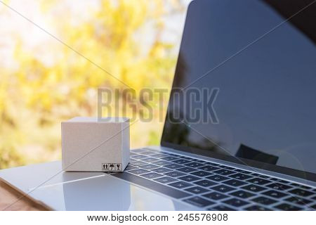 Mini Cardboard Box On Laptop Keyboard With Yellow Nature Background. Consumers Can Buy Products Dire
