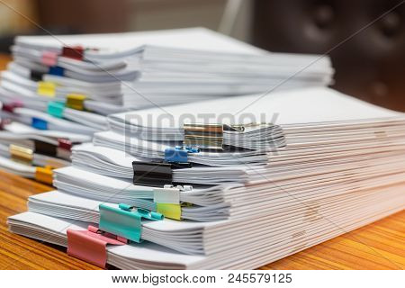Close Up Pile Of Unfinished Paperwork On Office Desk Waiting To Be Managed. Stack Of Homework Assign