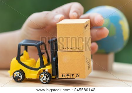 Handle Cardboard Boxes On Mini Forklift Trucks With Nature Background And Globe Nearby. Logistics An