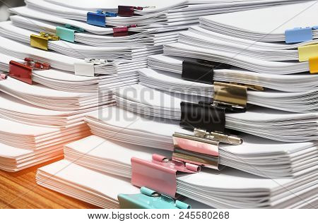 Close Up Pile Of Unfinished Paperwork Separated By Colorful Binder Clips On Office Desk Waiting To B