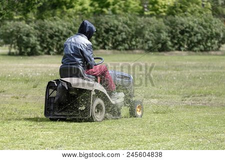 A Man On A Tractor Lawn Mower Mows The Grass