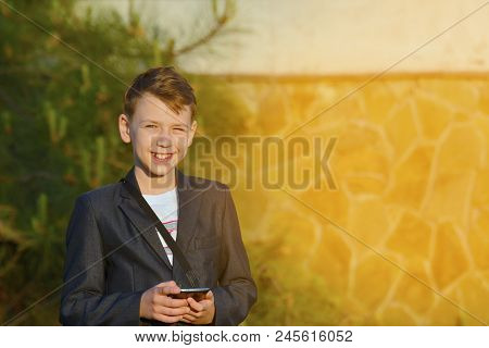 A Boy With A Smartphone Reads A Message In The Smartphone And Looks At The Camera.