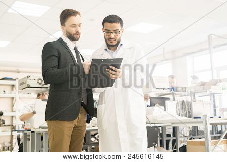 Handsome Arabian Technician Wearing Lab Coat And Potential Investor Discussing Details Of Their Coop